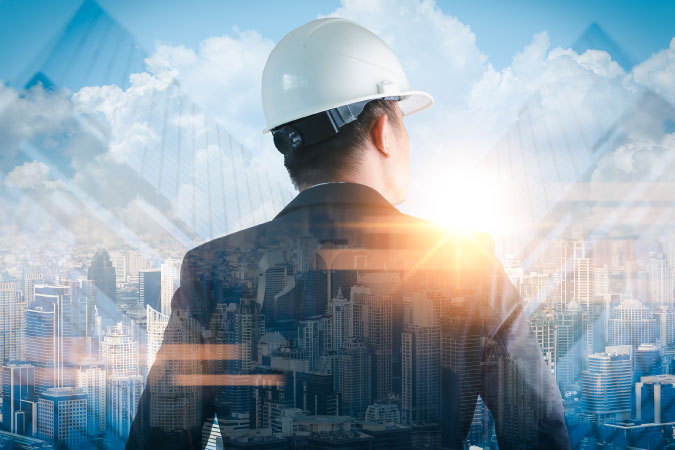 Businessman with hard hat looking at building city view